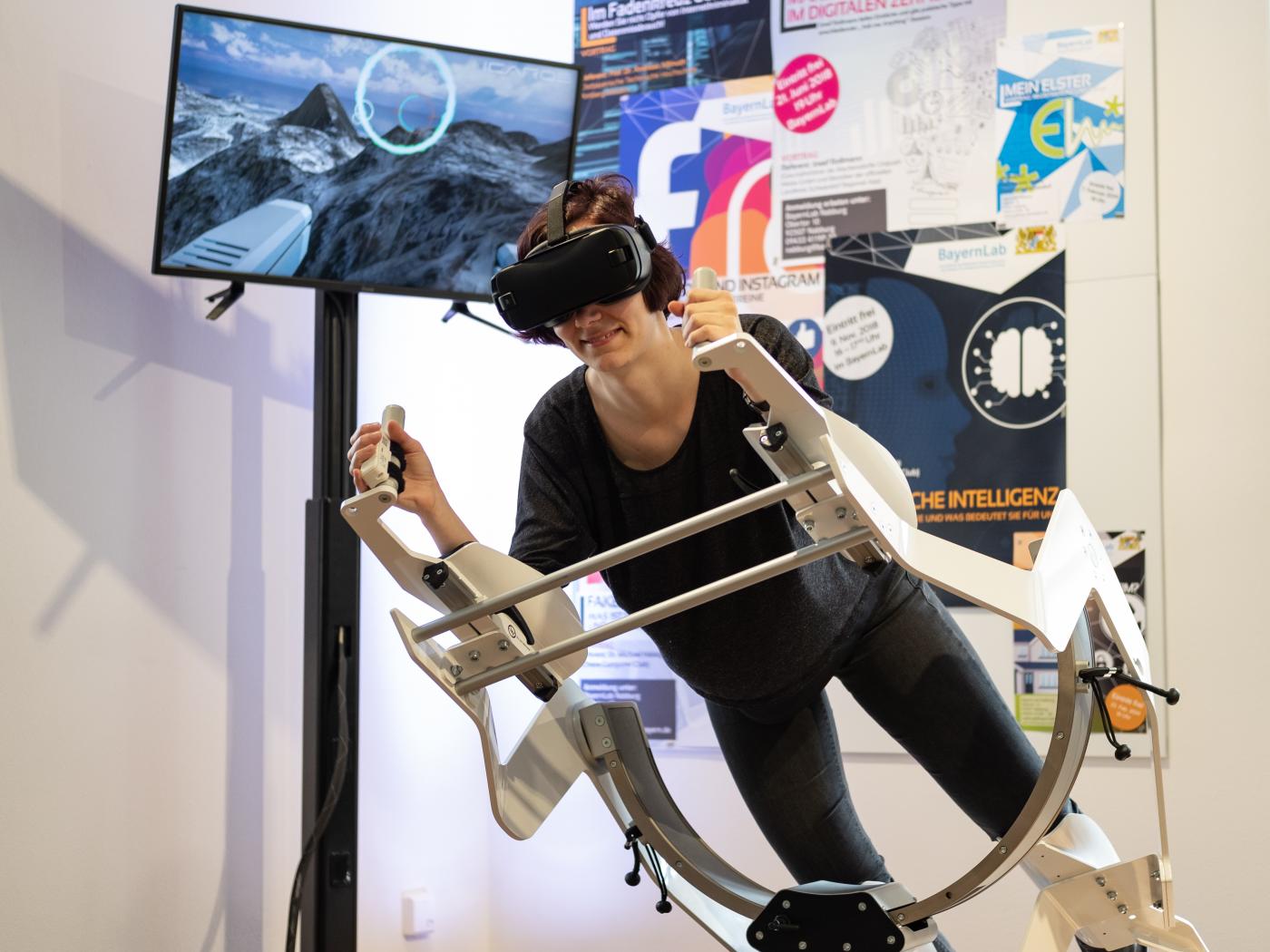 Der Icaros - die neue Fitness-Dimension. Auf dem Icaros-Gestell ist eine Frau in der Blank mit einer VR-Brille und testet den Icaros