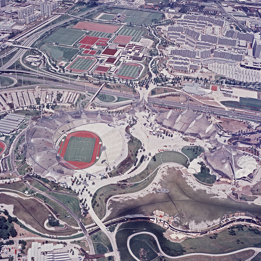 Schrägluftbild des Olympiageländes in München mit Stadion und weiteren Sport- und Wohnanlagen.