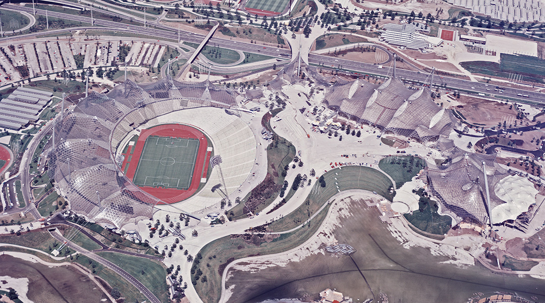 Schrägluftbild des Olympiageländes in München mit Stadion und weiteren Sport- und Wohnanlagen.