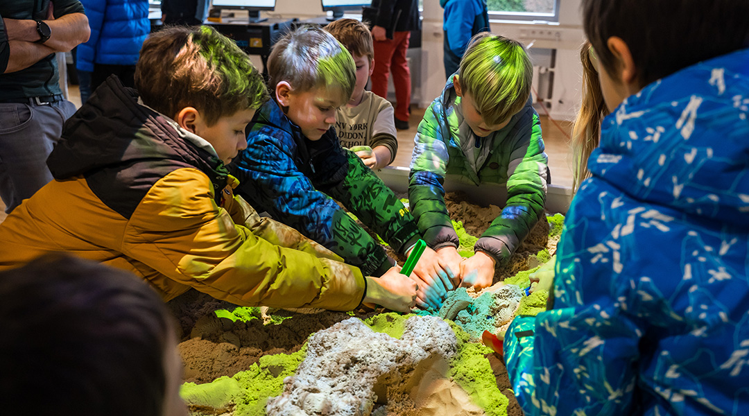 Kinder graben zusammen in der Augmented Reality Sandbox im BayernLab